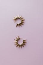 Gold spiked 2" hoop earrings on pink background