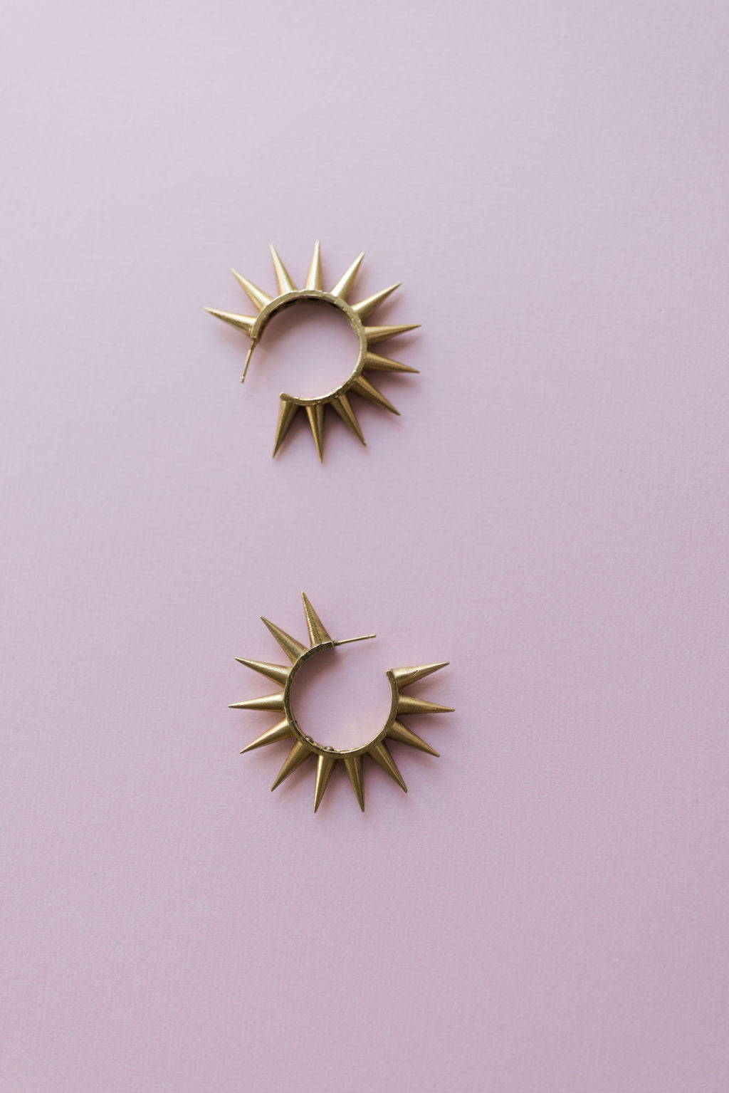 Gold spiked 2" hoop earrings on pink background